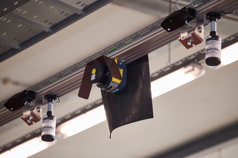 Blick auf die Sicherheitstechnik im Übergabebereich: Ein Sicherheits-Laserscanner RSL 400 von Leuze Blick auf die Sicherheitstechnik im Übergabebereich: Ein Sicherheits-Laserscanner RSL 400 von Leuze